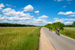 kleine Gruppe Radfahrer trainiert in schöner Landschaft auf einer Landstraße im Sommer. Am Wegesrand blühen bunte Blumen