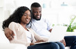 © Prostock-studio - Black man and woman using laptop, sitting on couch together