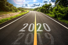 The Word 2020 Written On Highway Road In The Middle Of Empty Asphalt Road At Golden Sunset And Beautiful Blue Sky. Concept For New Year 2020. 