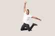 © fizkes - Happy joyful black man jumping high in photo studio.