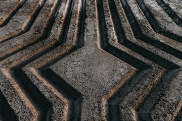 Relief gray reinforced concrete wall with curved extruded stripes with a diamond shape in the center