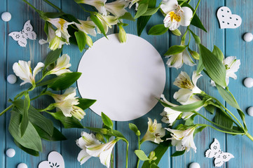Mock up blank paper and envelope on blue wooden background with natural flowers of white color. Blank, frame for text. Greeting card design with flowers. Aalstroemeria on wooden background.