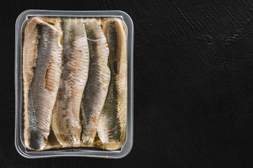 Marinated fillet mackerel or fillet herring fish with oil packed in box on slate stone background. Mediterranean food, appetizer, seafood, top view