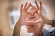 Cute senior old business woman making a heart shape with her hands and fingers
