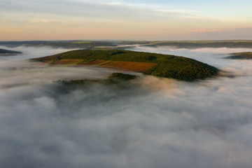 Wall Mural - Canyon river in fog shooting from the air