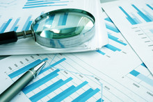 Assessment And Audit. Business Papers With Financial Charts And Magnifying Glass.