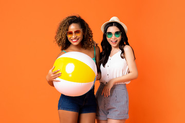 Happy African American and Asian woman friends with colorful beach ball