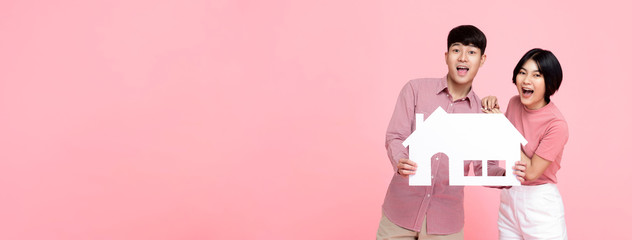 Asian couple holding paper home on pink banner background