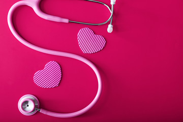 Stethoscope with hearts on color background