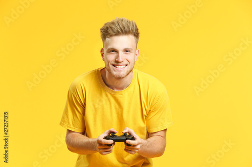 Portrait of handsome young man playing video games on color background Canvas Print