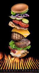 Hamburger ingredients falling down one by one on burning grill grate. Colorful conceptual picture of burger cooking.