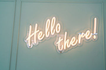 neon glowing sign with word hello there and green wall