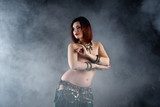 Sexy women performs belly dance in ethnic dress on dark smoky background, abstract art photography