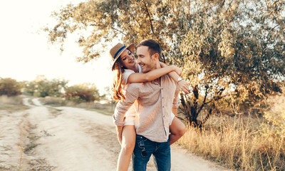 Stylish couple walking outdoors in lawn with a glass of wine. Man and woman looking at each other and walking together outdoors.