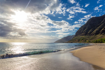 Wall Mural - Evening view with sun shining throug clouds at Makua beach, Oahu, Hawaii