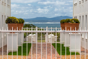 Wall Mural - Seascape view between two white buildings and white fence in foreground