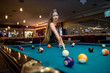 © RomanR - Young and beautiful woman in pub playing billiard