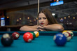 © RomanR - Beautiful woman looking at billiard balls on table