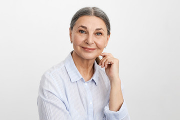 Wall Mural - Beauty, people, mature age and lifestyle concept. Studio picture of adorable charming elderly retired female with wise blue eyes and few wrinkles looking at camera with happy cheerful smile