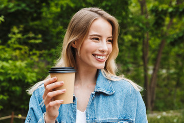 Canvas Print - Photo closeup of cute caucasian woman drinking coffee while walking in green park