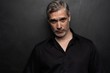 © opolja - Middle-aged good looking man posing in front of a black background with copy space.