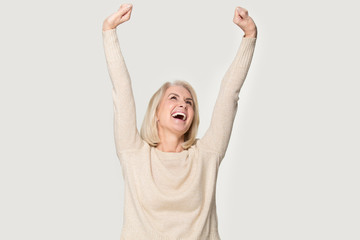 Excited senior woman raised stretched hands feels happy studio shot