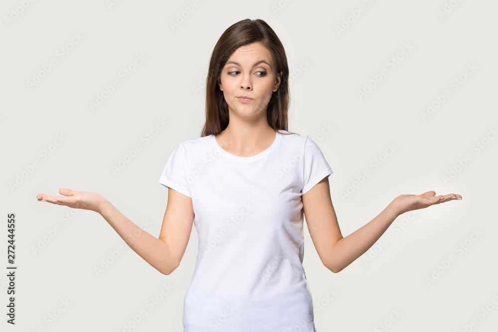 Millennial woman stretched hands thinking makes choice on grey background - obrazy, fototapety, plakaty 