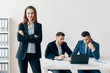 © GVS - Portrait of young smiling business woman with crossed arms and her business team on background