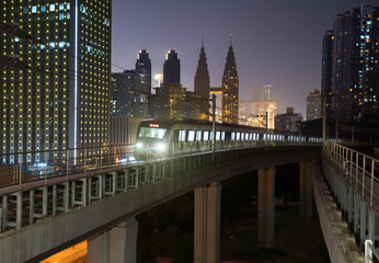 Wall Mural - At night, the light rail train shuttles through the city.