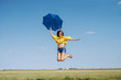 © Dusan Petkovic - Cheerful Caucasian teenage girl in yellow blouse, denim shorts and with eyeglasses jumping outdoor with blue umbrella in hand.