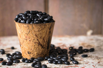 Wall Mural - Black beans in Bio cup on wooden background.