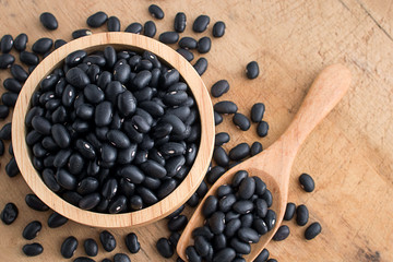 Wall Mural - Raw black beans in wooden bowl and spoon on table.