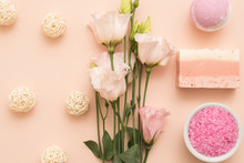 Spa Body Care Products. Flat Lay With Handmade Soap, Bath Salt And Delicate Flowers Arranged On Peach Color Background.