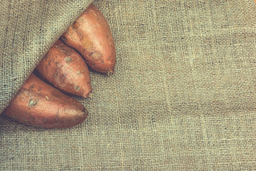 Wall Mural - Raw sweet potatoes on a  jute backgroud. Product photo of batats. Healthy diet for vegetarians and vegans. Source of vitamins. 