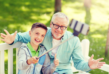 Canvas Print - family, generation, technology and people concept - happy grandfather and grandson taking picture with smartphone selfie stick at summer park