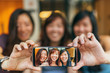 © Santi Nunez/Stocksy - Asian friends women taking a selfie in the coffee shop.
