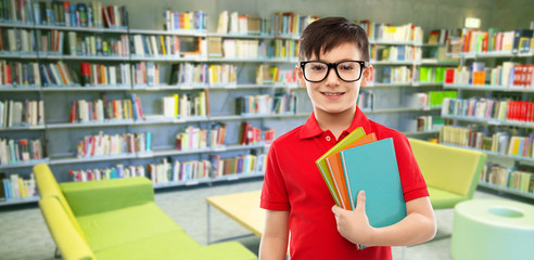 Poster - school, education and people concept - portrait of smiling little student boy in red polo t-shirt in glasses with books over reading room of library background