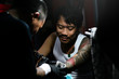 © Santi Nunez/Stocksy - Professional asian tattooer makes a tattoo