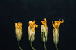 © Vera Lair/Stocksy - Group of zucchini blossom on black background