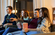 © Syda Productions - friendship and leisure concept - friends with popcorn and remote control watching tv at home at night