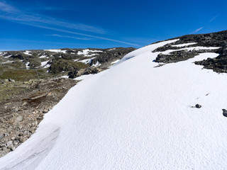 Wall Mural - Snow lies in mountains on the sides of mountain road Aurlandsvegen, Aurland, Norway