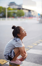 Asian Little Girl Kneeling On The Street, Playing Tired Look