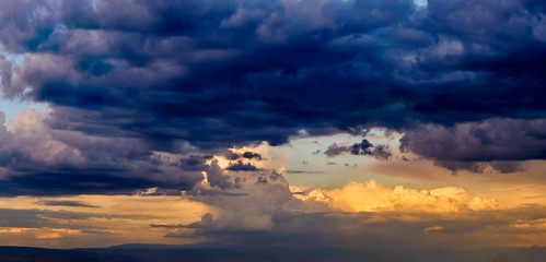 Wall Mural - dramatic light through the clouds against the backdrop of an exciting, bright stormy sky at sunset. 