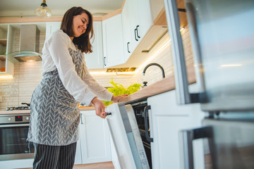 Wall Mural - young pretty woman putting dishes in dishwasher