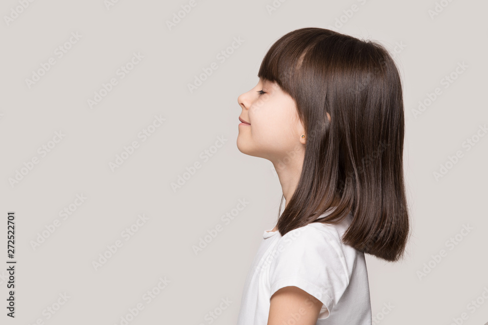 Profile of serene little girl isolated on grey studio background - obrazy, fototapety, plakaty 