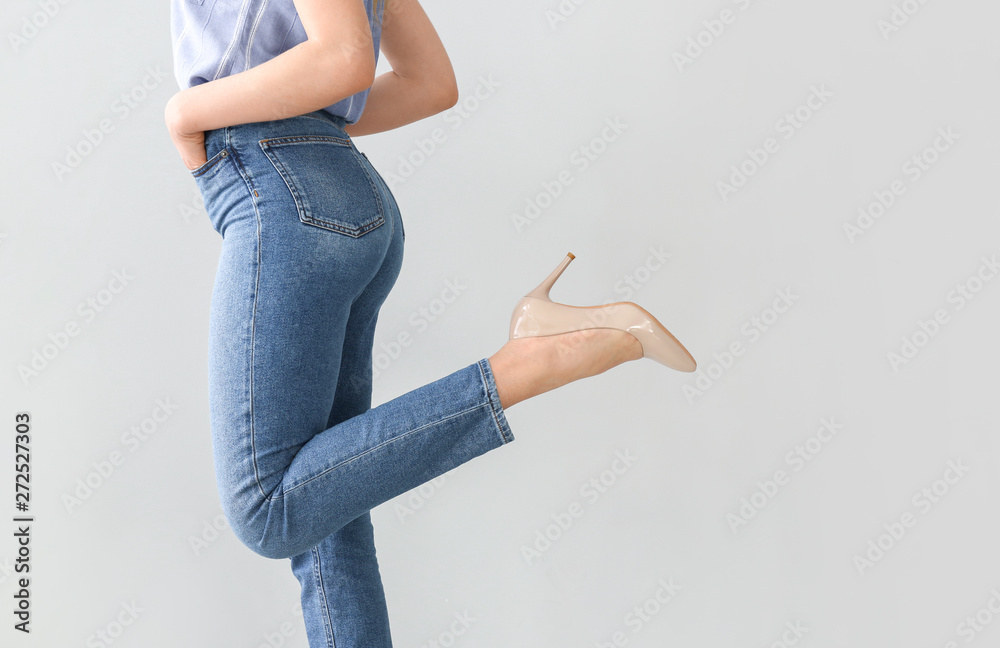 Young woman wearing stylish jeans pants on light background
