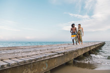 Multicultural Couple Walking Together On Wooden Dock Over The Mediterranean Sea