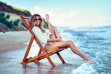 Pretty Woman Relaxing On A Lounger Beach And Drinks Soda Water. Summer Vacation Concept.