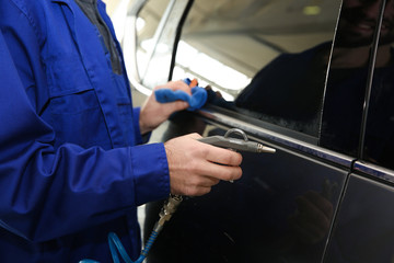 Canvas Print - Worker cleaning automobile with gun and rag at car wash, closeup