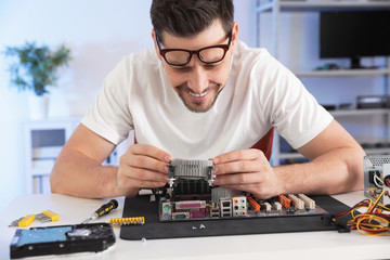 Canvas Print - Male technician repairing motherboard at table indoors